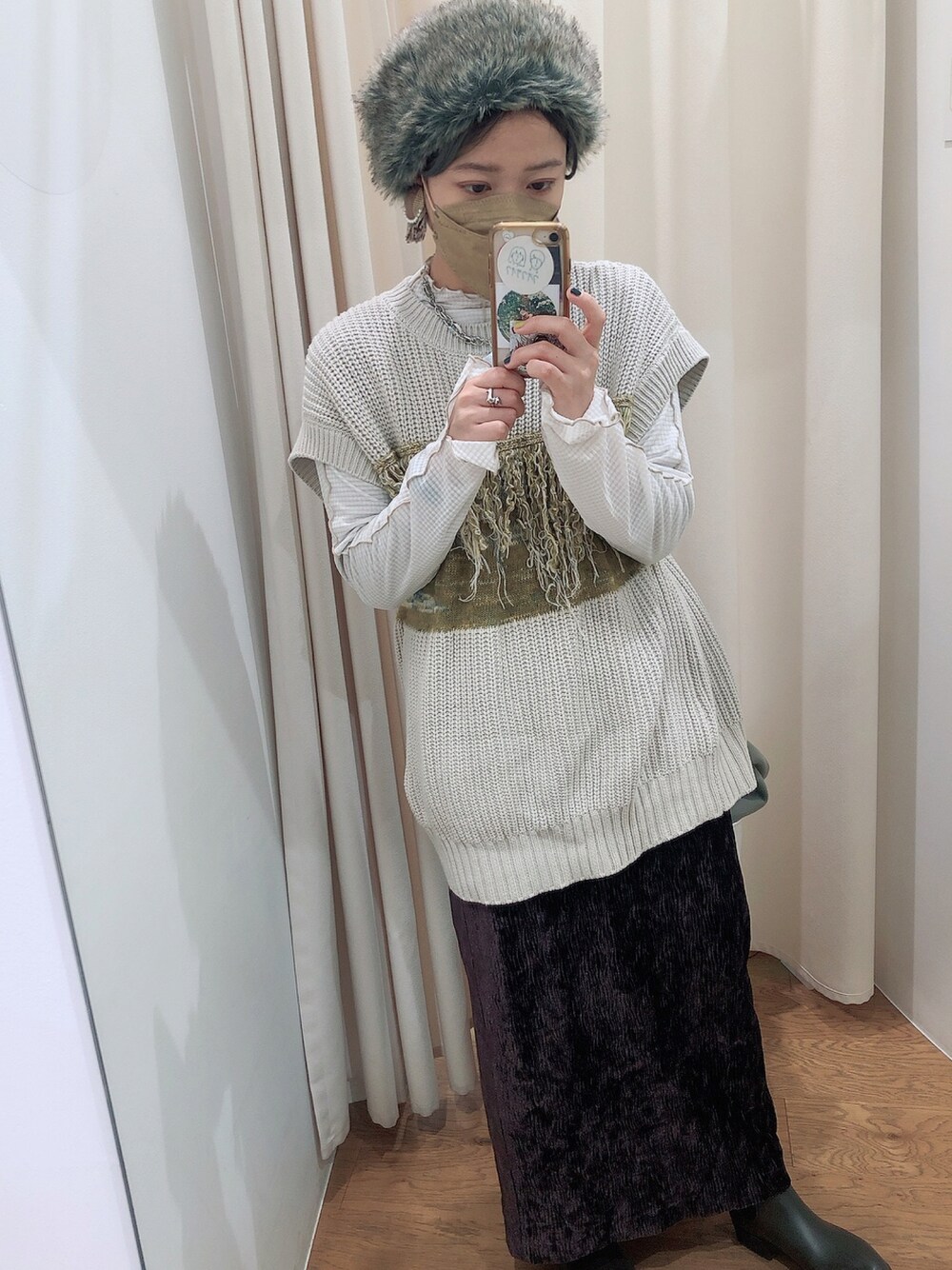 グレー系のベスト、ブラウン系のスカート、ホワイト系のTシャツ/カットソーを着用したレディースの秋コーディネートの1枚目の写真
