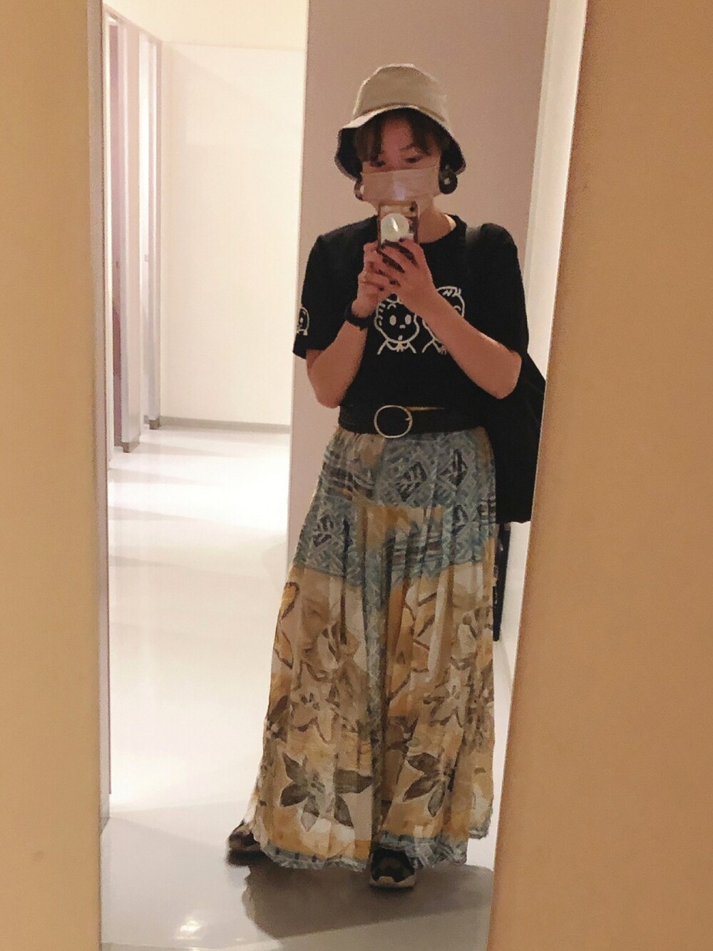 イエロー系のスカート、ブラック系のTシャツ/カットソー、ブラック系のスニーカーを着用したレディースの夏コーディネートの1枚目の写真