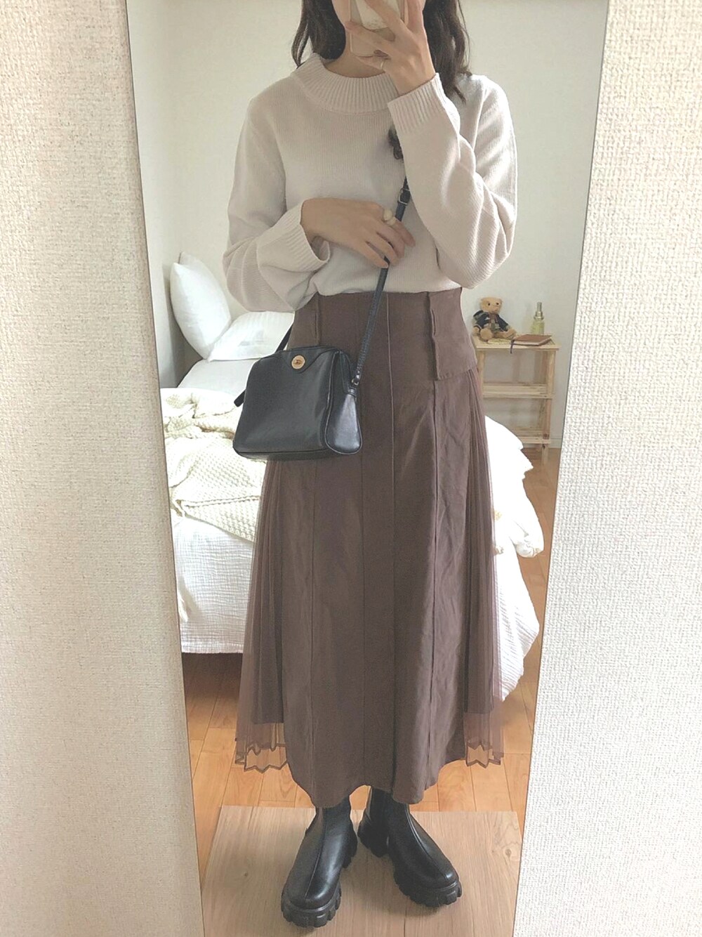 ブラック系のショルダーバッグ、ブラウン系のスカート、ブラック系のブーツを着用したレディースの秋コーディネートの1枚目の写真