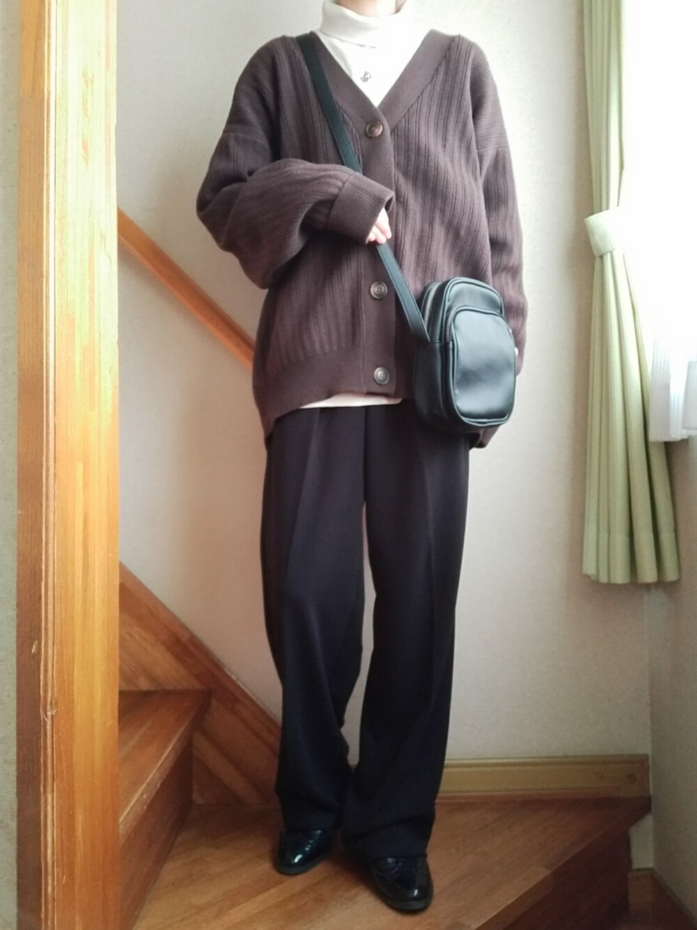 ベージュ系のTシャツ/カットソー、ブラウン系のカーディガン/ボレロ、ブラック系のショルダーバッグを着用したレディースの冬コーディネートの1枚目の写真