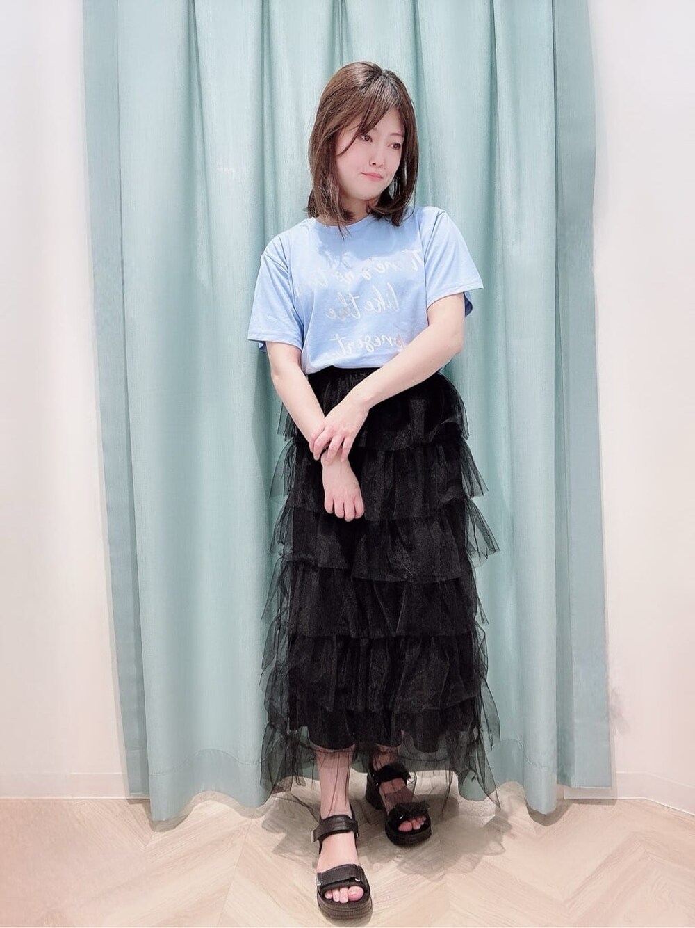 ブルー系のTシャツ/カットソー、ブラック系のスカート、ブラック系のサンダルを着用したレディースの夏コーディネートの1枚目の写真