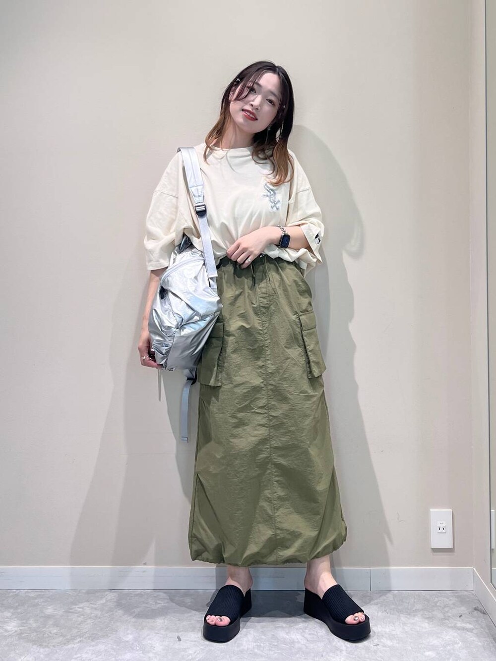 ブラック系のサンダル、シルバー系のバックパック/リュック、グリーン系のスカートを着用したレディースの春コーディネートの1枚目の写真