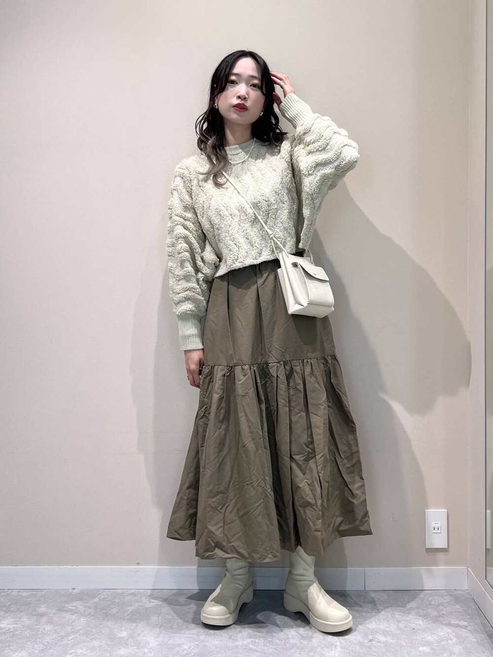 ホワイト系のショルダーバッグ、ホワイト系のブーツ、ホワイト系のニット/セーターを着用したレディースの冬コーディネートの1枚目の写真