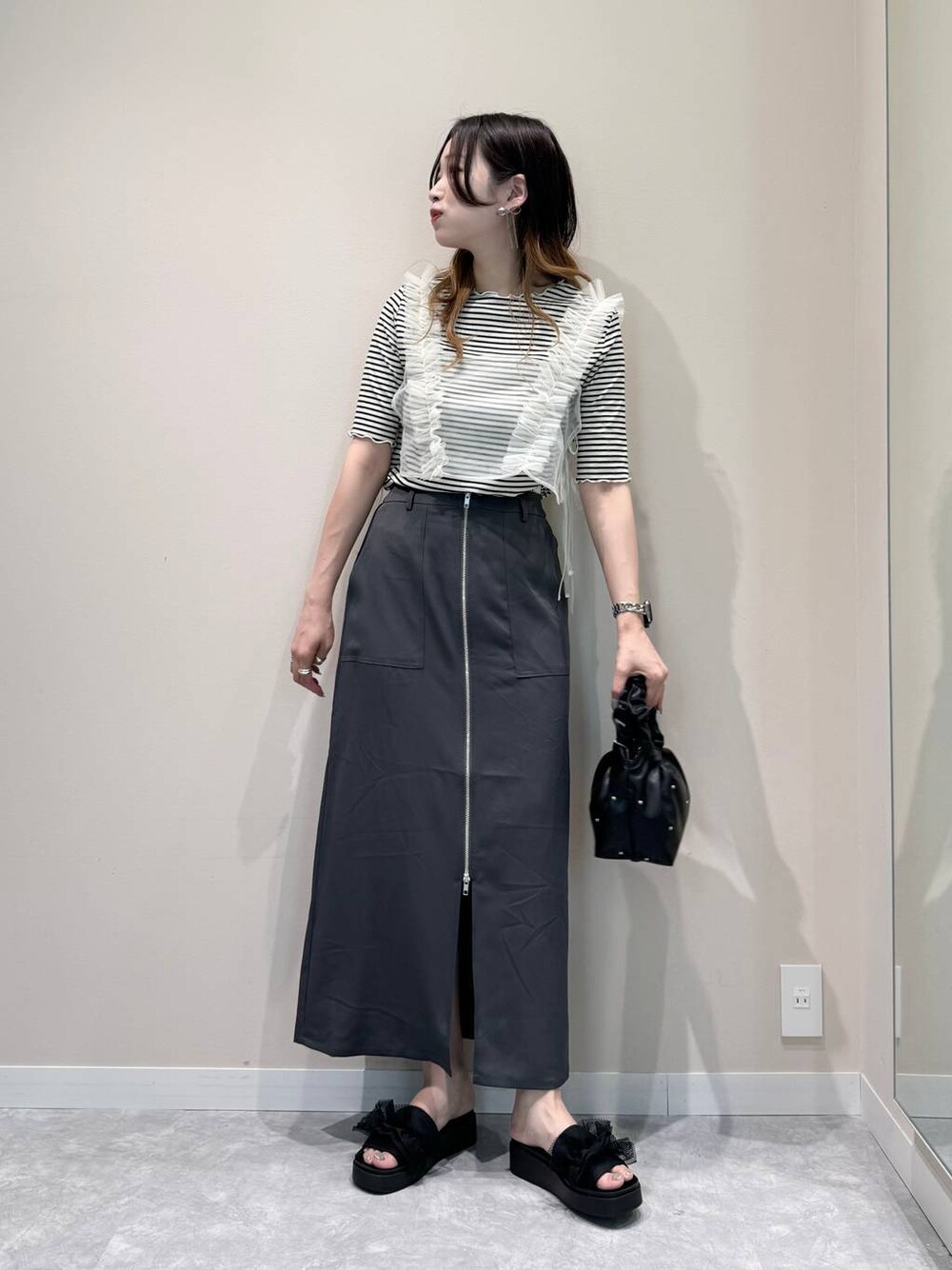 ブラック系のハンドバッグ、ブラック系のサンダル、ホワイト系のTシャツ/カットソーを着用したレディースの夏コーディネートの1枚目の写真