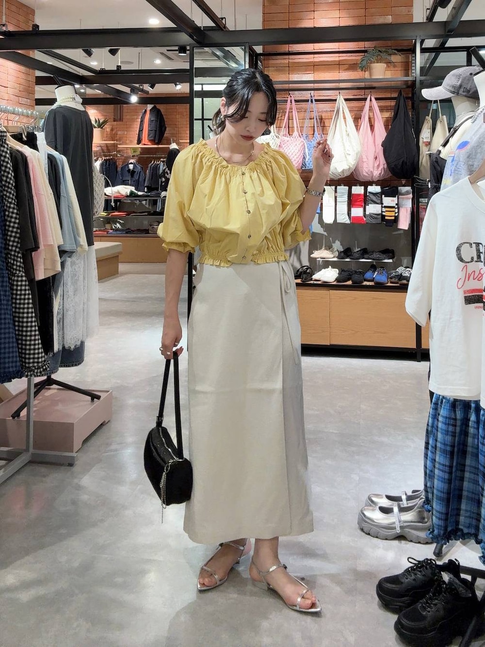 ホワイト系のスカート、ブラック系のトートバッグ、シルバー系のサンダルを着用したレディースの春コーディネートの1枚目の写真