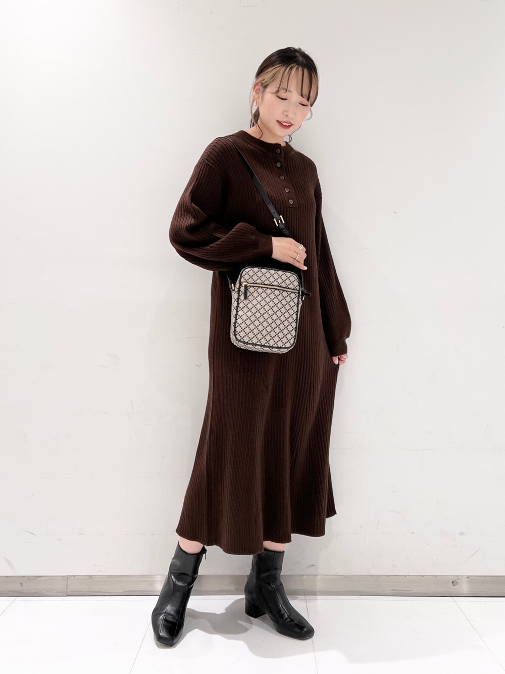 ブラウン系のワンピース、ブラック系のブーツ、ブラック系のショルダーバッグを着用したレディースの冬コーディネートの2枚目の写真