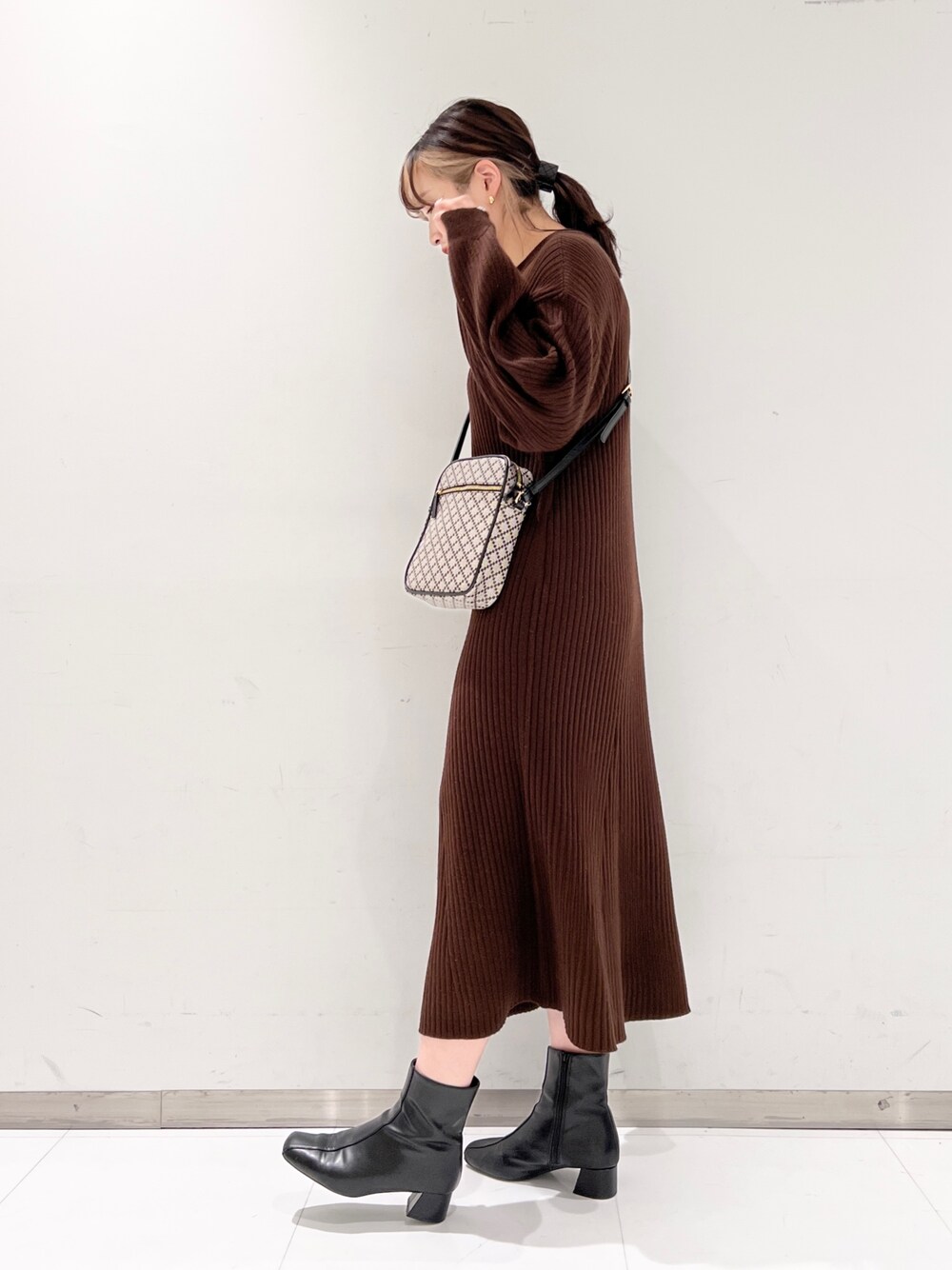 ブラウン系のワンピース、ブラック系のブーツ、ブラック系のショルダーバッグを着用したレディースの冬コーディネートの3枚目の写真