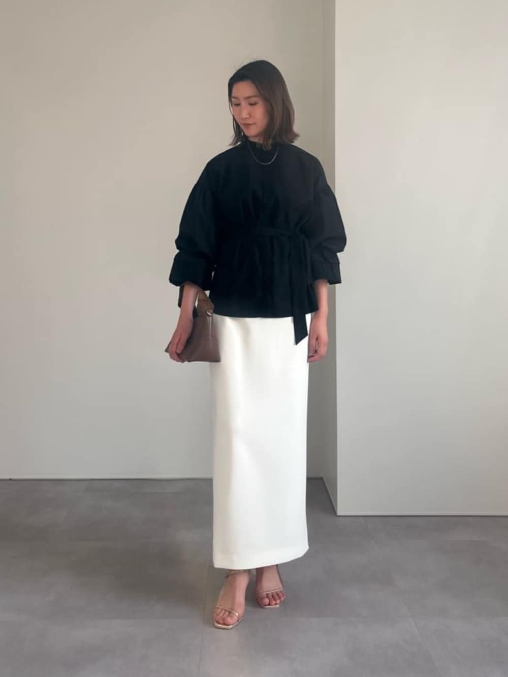 ゴールド系のサンダル、ホワイト系のスカート、ブラック系のシャツ/ブラウスを着用したレディースの春コーディネートの1枚目の写真