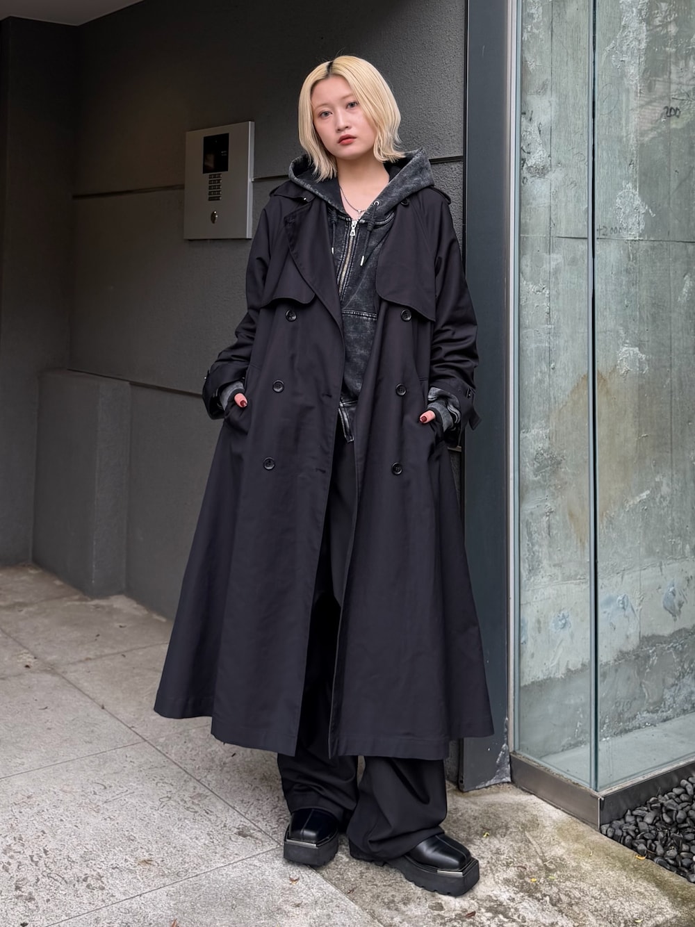 ブラック系のパーカー、グレー系のカーゴパンツ、ブラック系のトレンチコートを着用したレディースの秋コーディネートの1枚目の写真