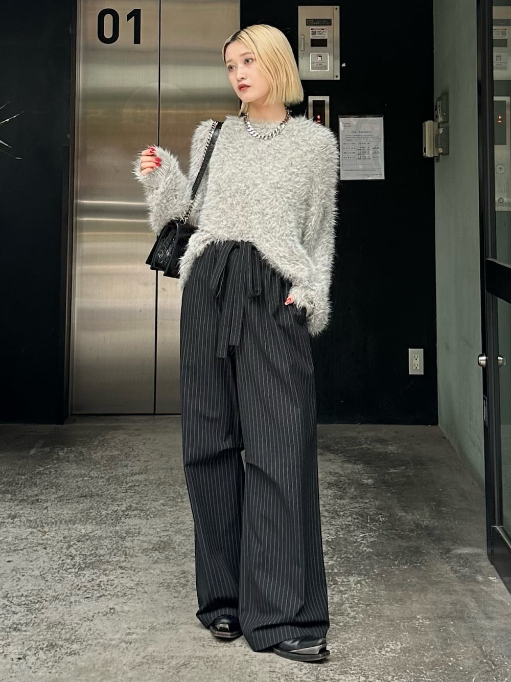 グレー系のニット/セーター、ブラック系のその他パンツ、シルバー系のネックレスを着用したレディースの秋コーディネートの1枚目の写真