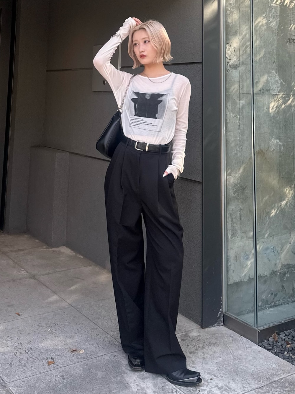 ブラック系のスラックス、ブラック系のショルダーバッグ、ホワイト系のTシャツ/カットソーを着用したレディースの夏コーディネートの1枚目の写真