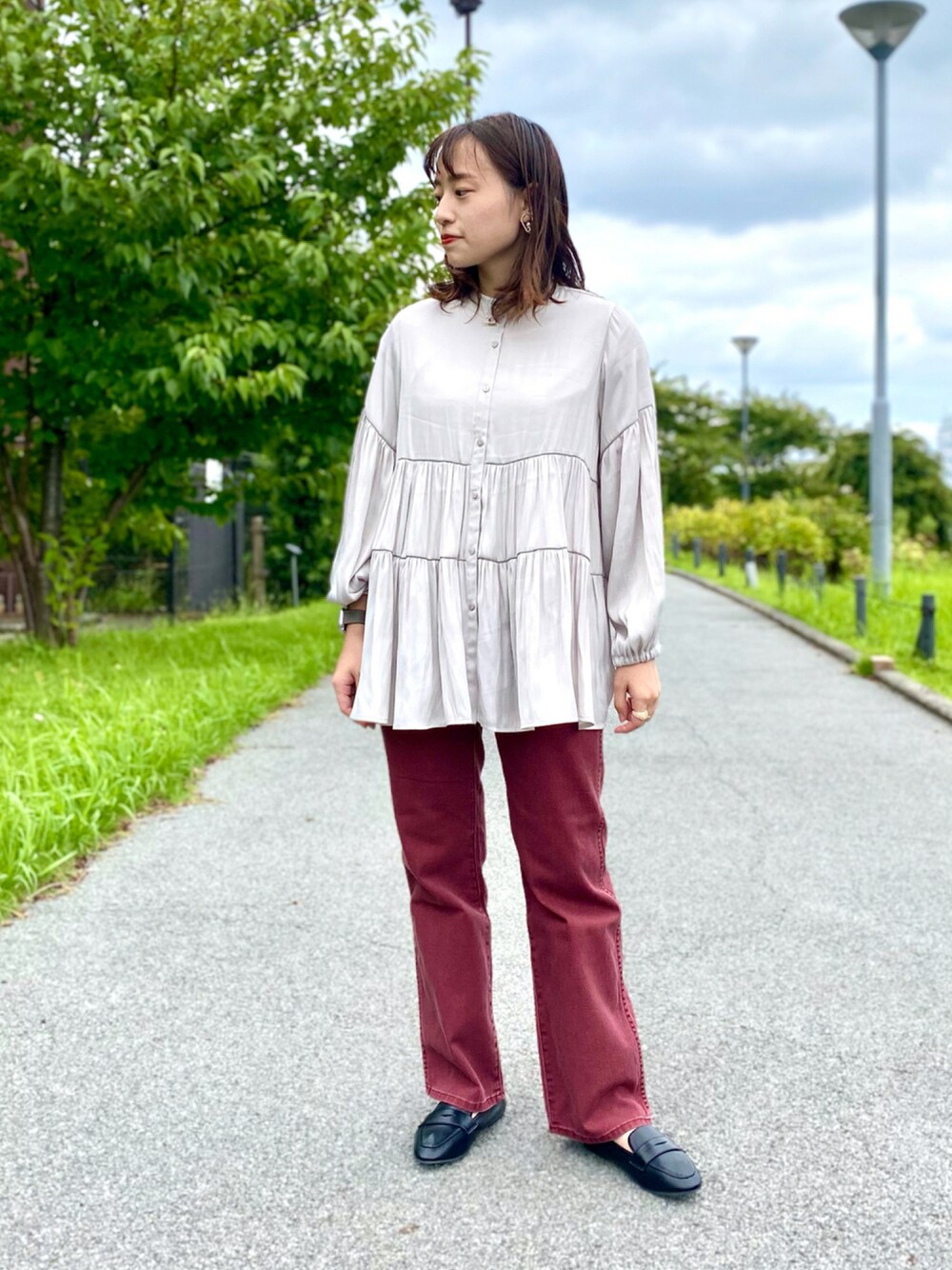 レッド系のデニムパンツ、ブラック系のローファー、ベージュ系のシャツ/ブラウスを着用したレディースの秋コーディネートの1枚目の写真