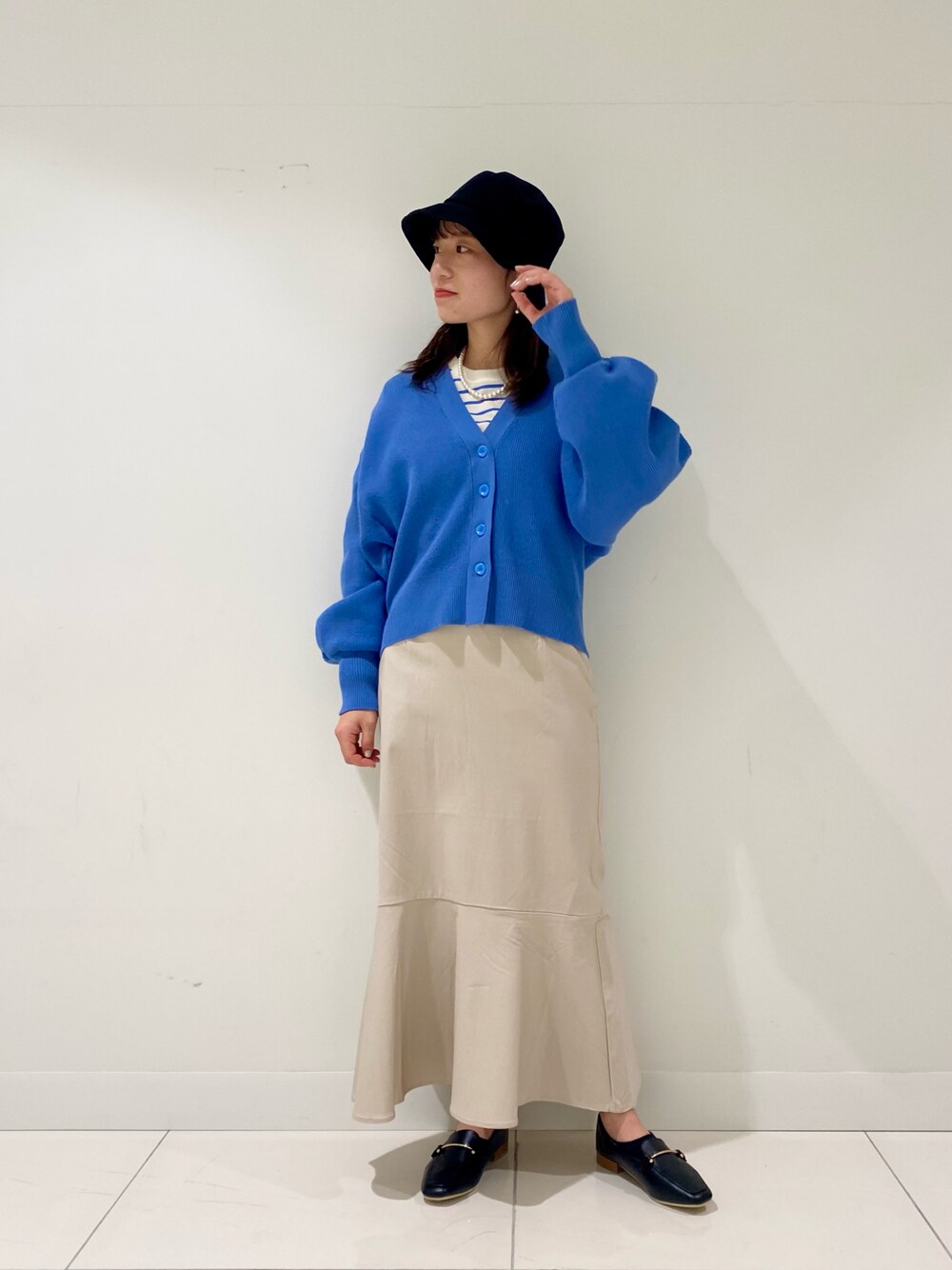 ブルー系のカーディガン/ボレロ、ブルー系のTシャツ/カットソー、ベージュ系のスカートを着用したレディースの冬コーディネートの1枚目の写真