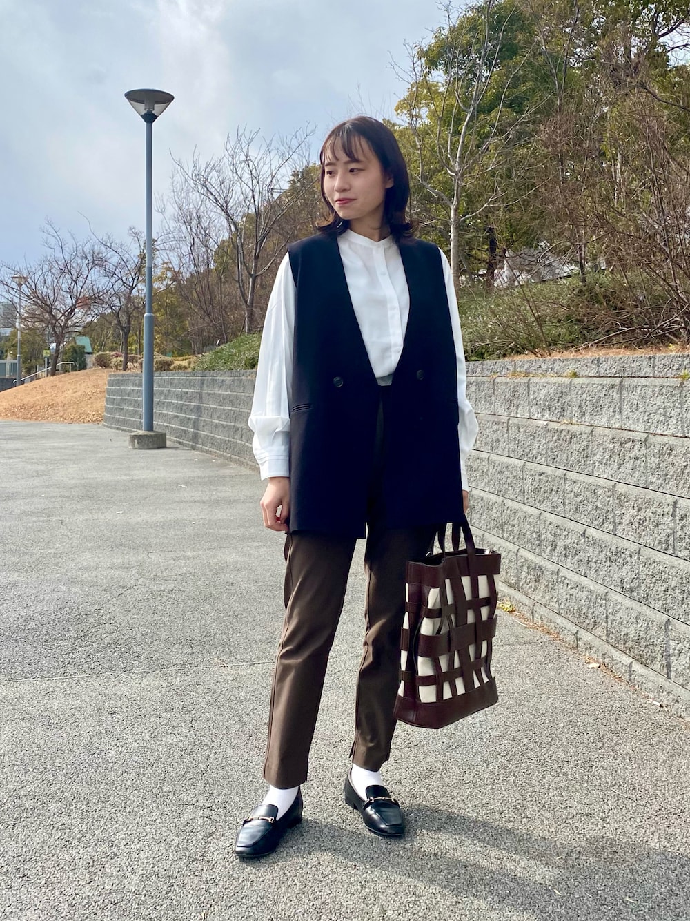 ホワイト系のシャツ/ブラウス、ブラック系のベスト、ブラウン系のその他パンツを着用したレディースの冬コーディネートの1枚目の写真