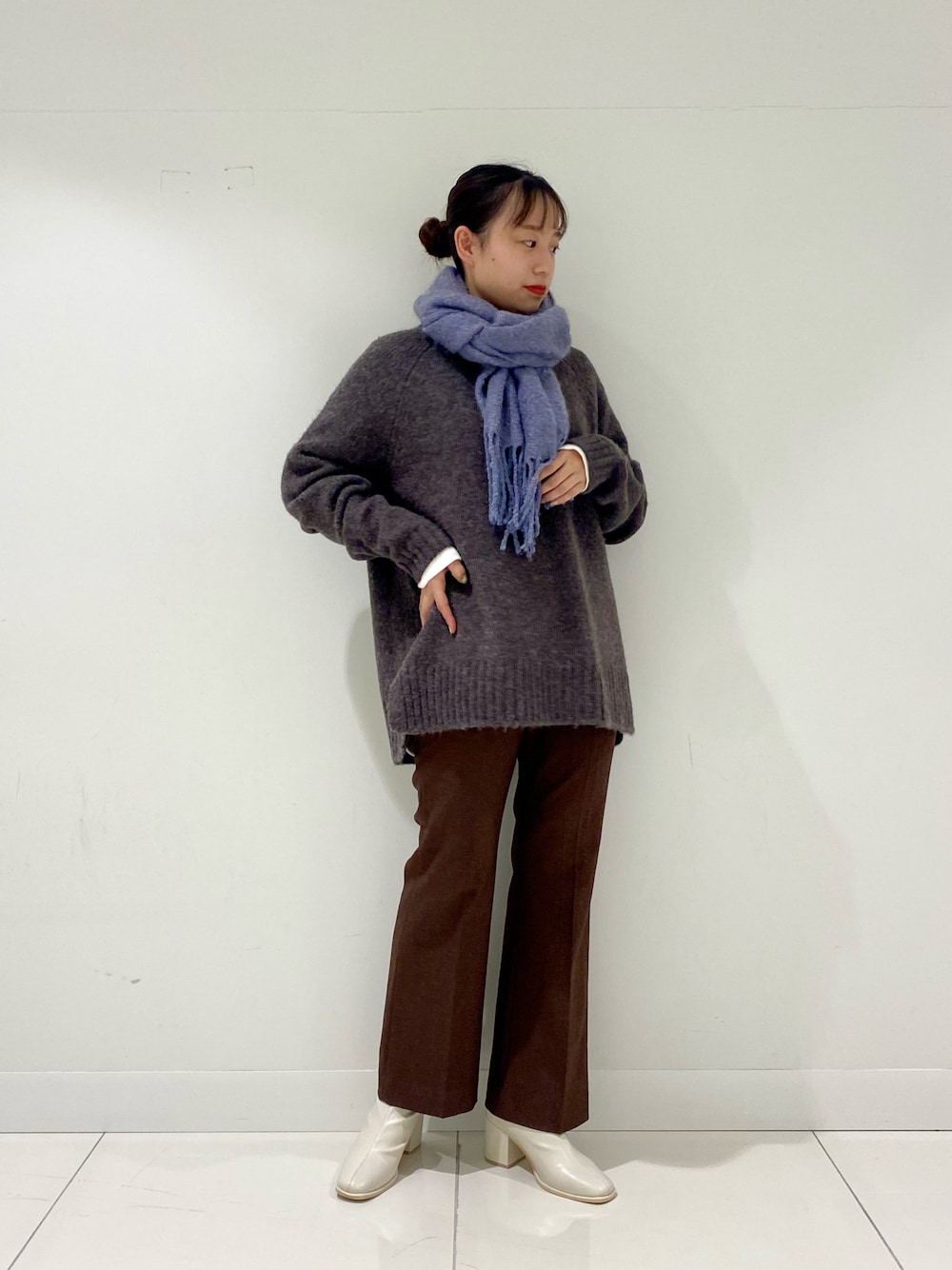 グレー系のニット/セーター、ホワイト系のTシャツ/カットソー、ホワイト系のブーツを着用したレディースの冬コーディネートの1枚目の写真