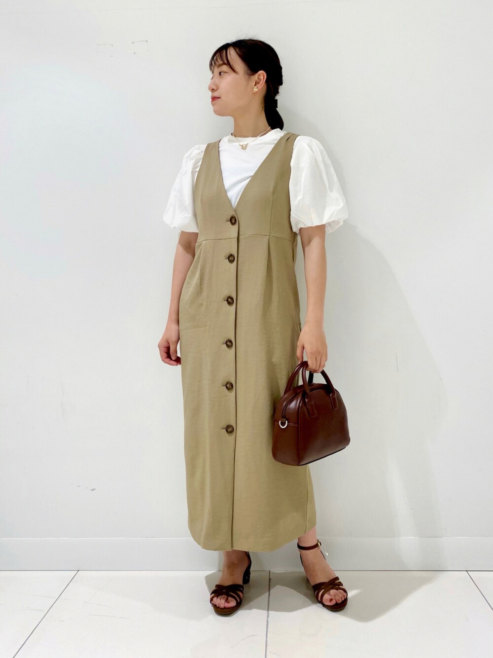 ブラウン系のショルダーバッグ、ベージュ系のジャンパースカート、ブラウン系のサンダルを着用したレディースの夏コーディネートの1枚目の写真
