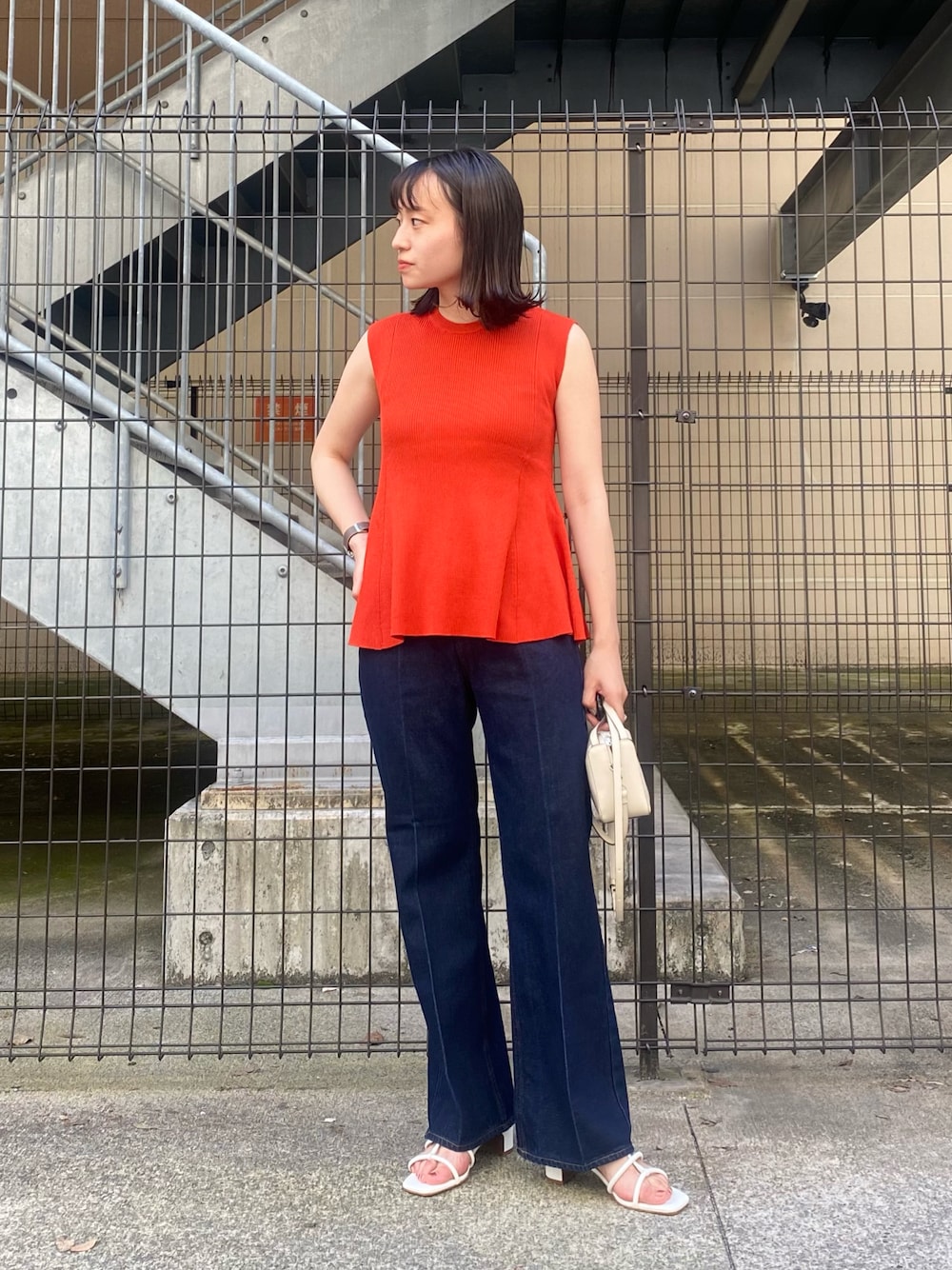 レッド系のニット/セーター、ブルー系のデニムパンツ、ホワイト系のショルダーバッグを着用したレディースの夏コーディネートの1枚目の写真