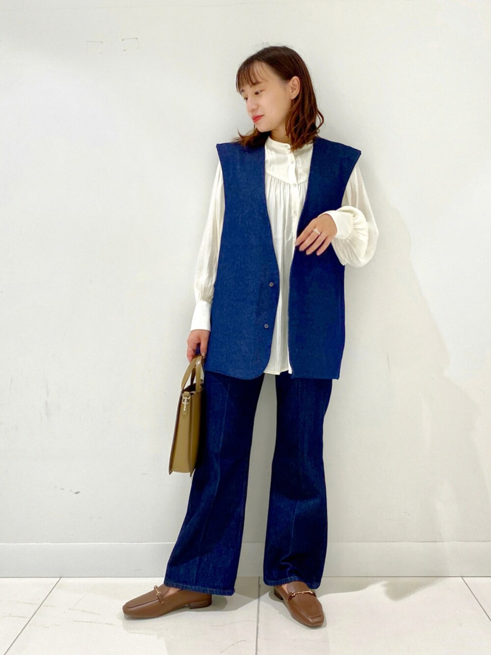 ホワイト系のシャツ/ブラウス、ブルー系のデニムパンツ、ブラウン系のローファーを着用したレディースの秋コーディネートの1枚目の写真