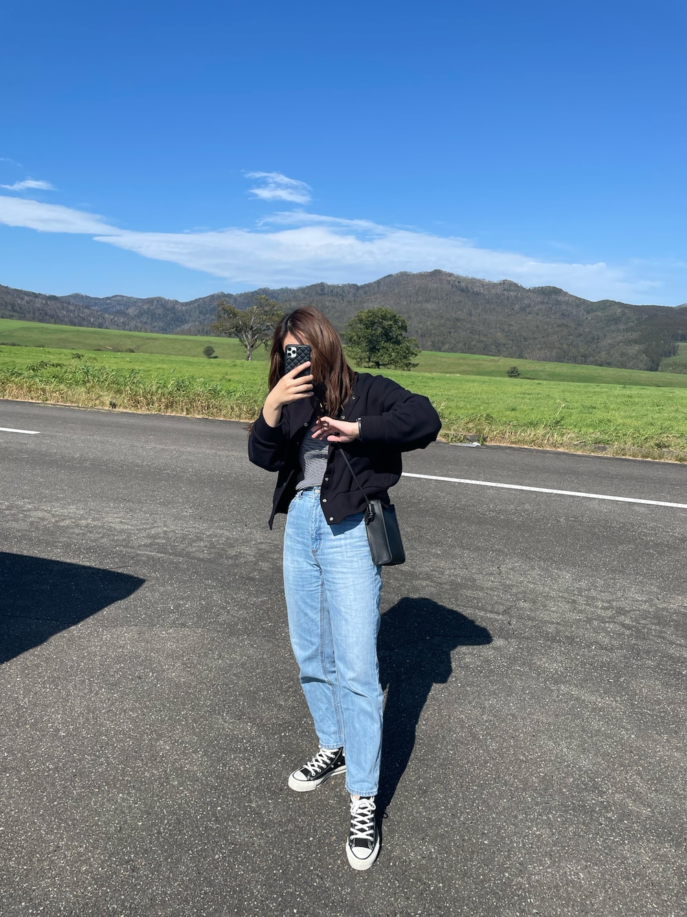 ブラック系のスニーカー、ブルー系のデニムパンツ、ブラック系のカーディガン/ボレロを着用したレディースの秋コーディネートの1枚目の写真