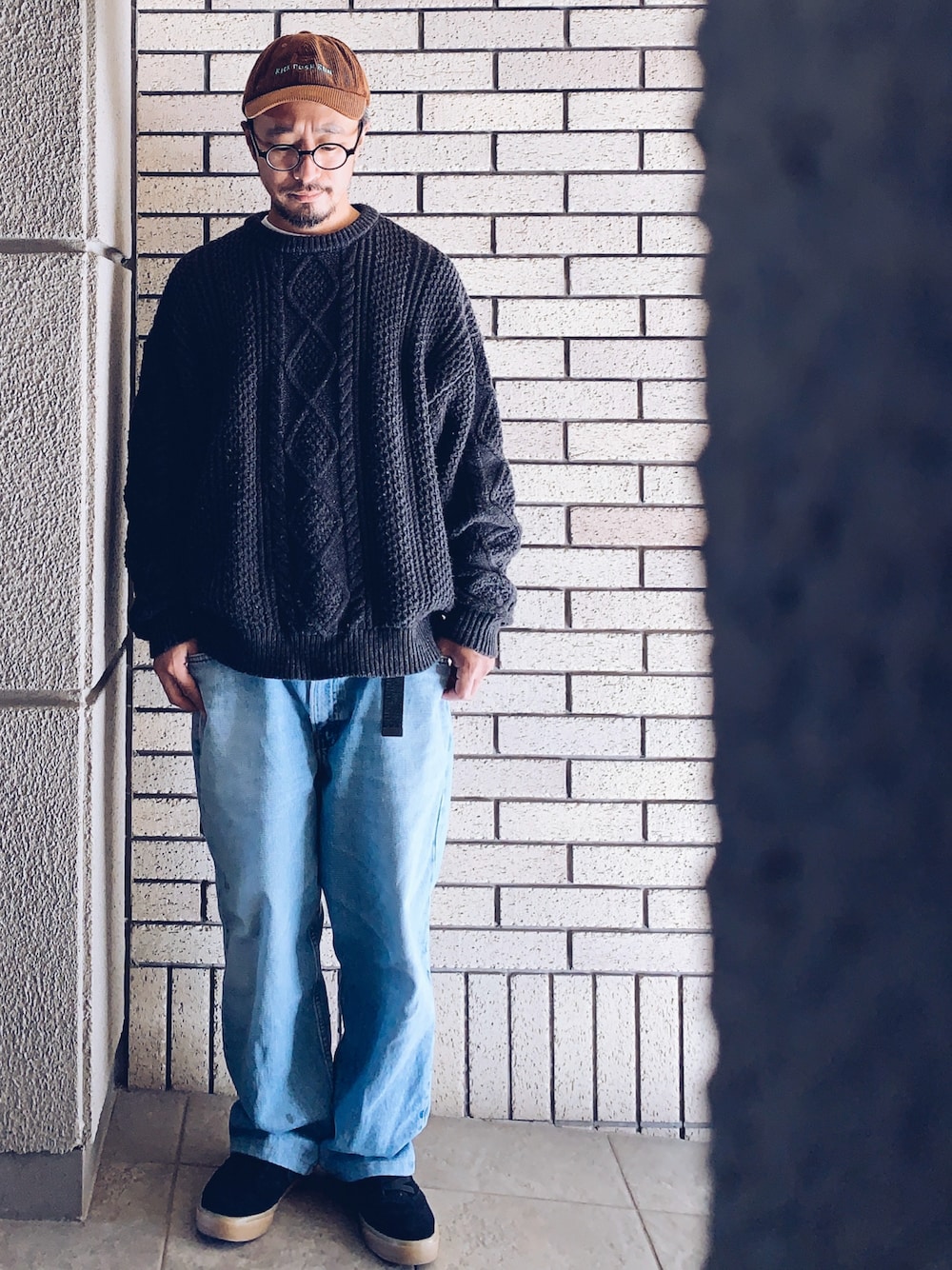 ブラック系のスニーカー、ブラック系のニット/セーター、ブルー系のデニムパンツを着用したメンズの秋コーディネートの1枚目の写真