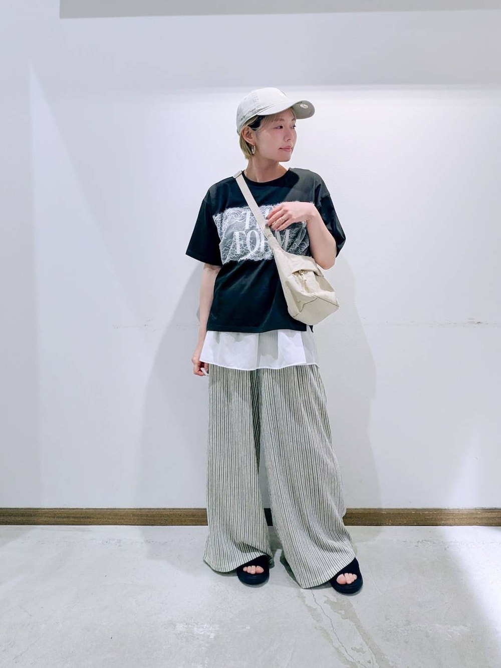 ホワイト系のタンクトップ、ベージュ系のショルダーバッグ、ブラック系のサンダルを着用したレディースの夏コーディネートの1枚目の写真