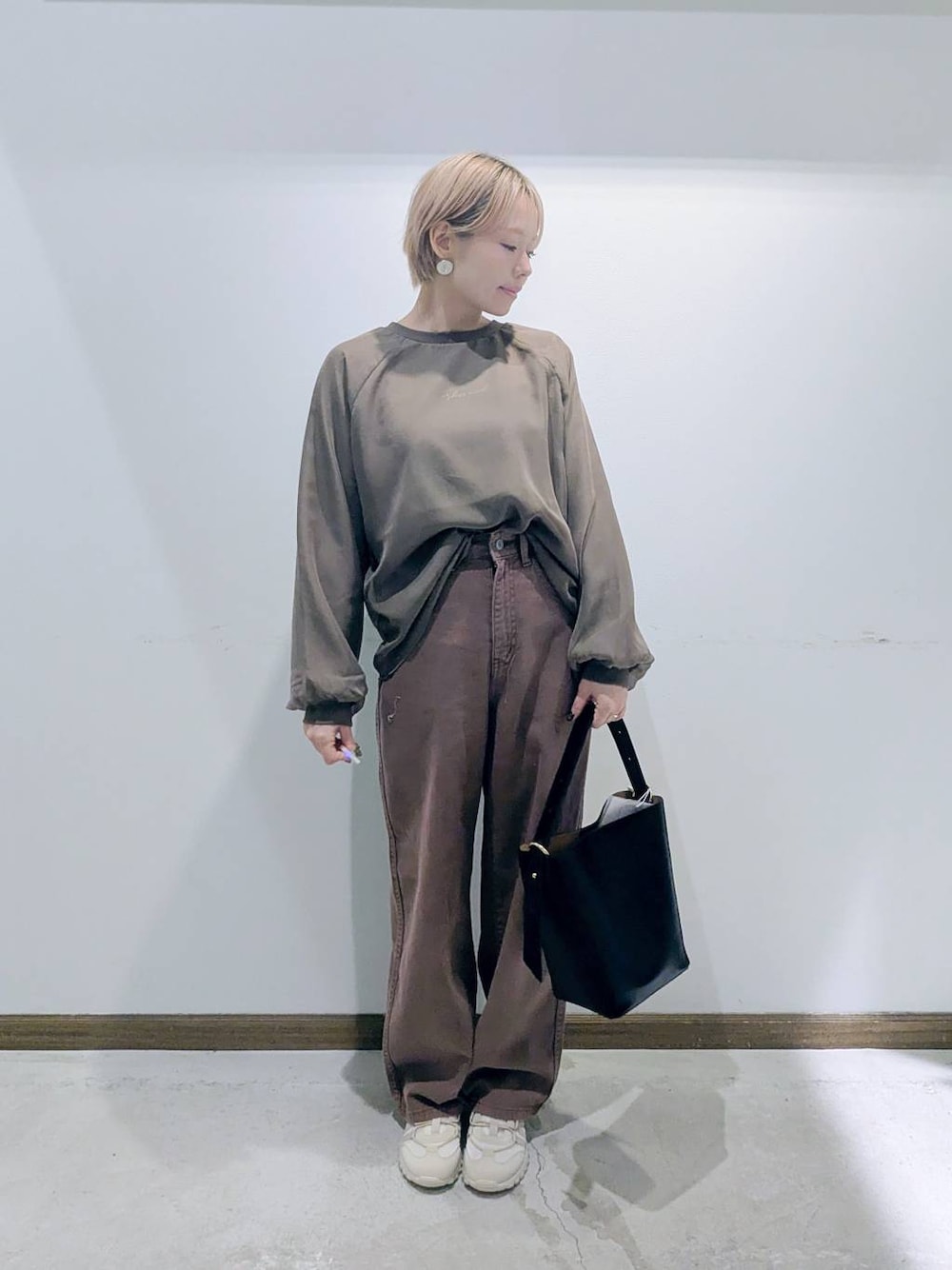 ブラック系のショルダーバッグ、ブラウン系のデニムパンツ、ブラウン系のTシャツ/カットソーを着用したレディースの秋コーディネートの1枚目の写真