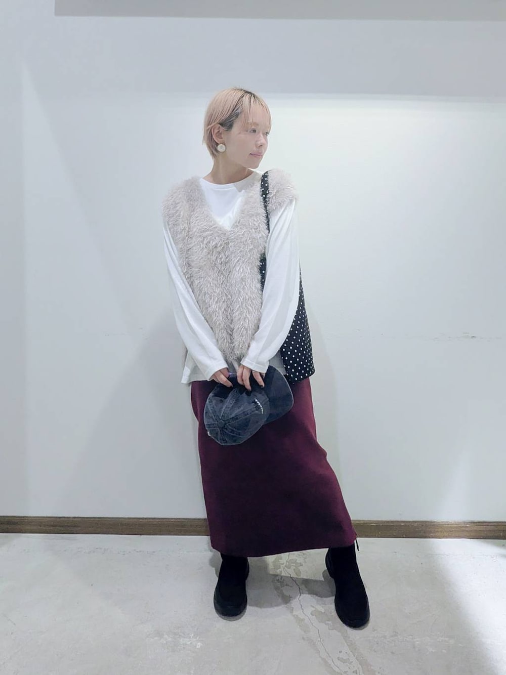 ブラック系のトートバッグ、レッド系のスカート、ブラック系のブーツを着用したレディースの秋コーディネートの1枚目の写真