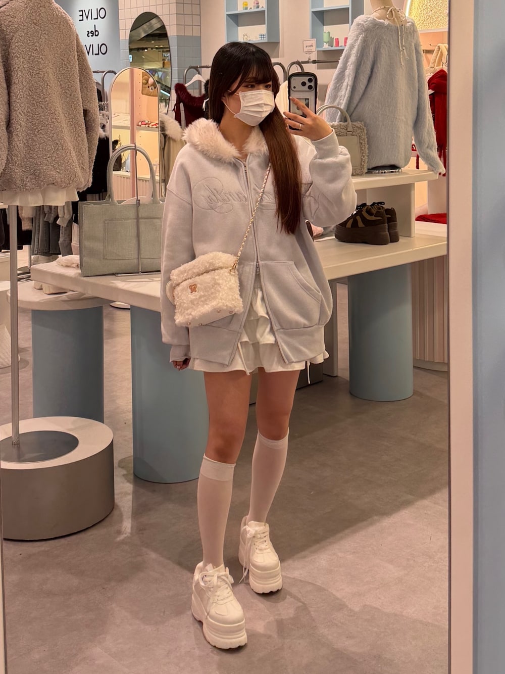 ブルー系のパーカー、ホワイト系のショルダーバッグ、ホワイト系のスカートを着用したレディースの冬コーディネートの1枚目の写真