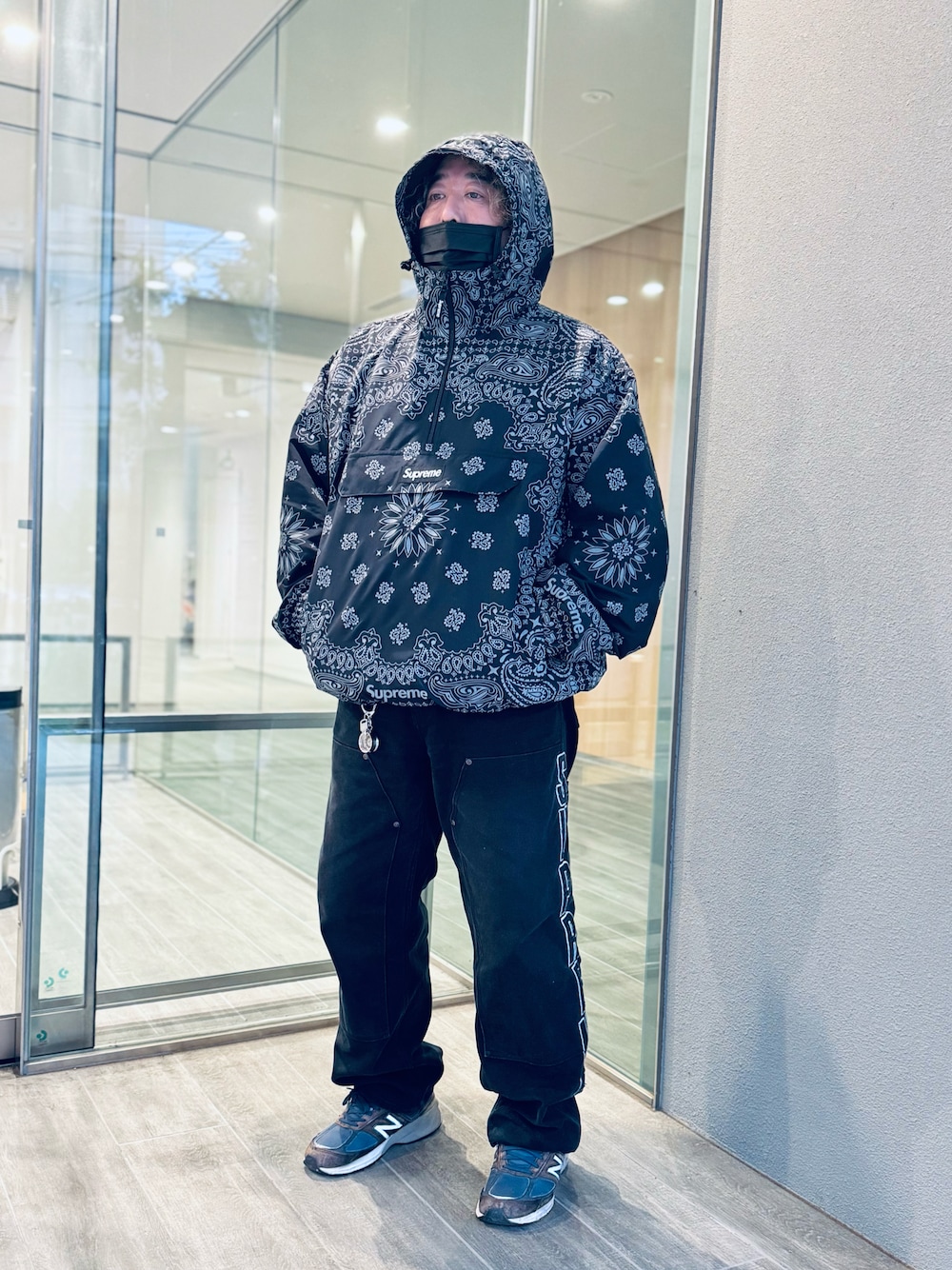 ブラック系のナイロンジャケット、ブラック系のデニムパンツ、ブルー系のスニーカーを着用したメンズの夏コーディネートの1枚目の写真