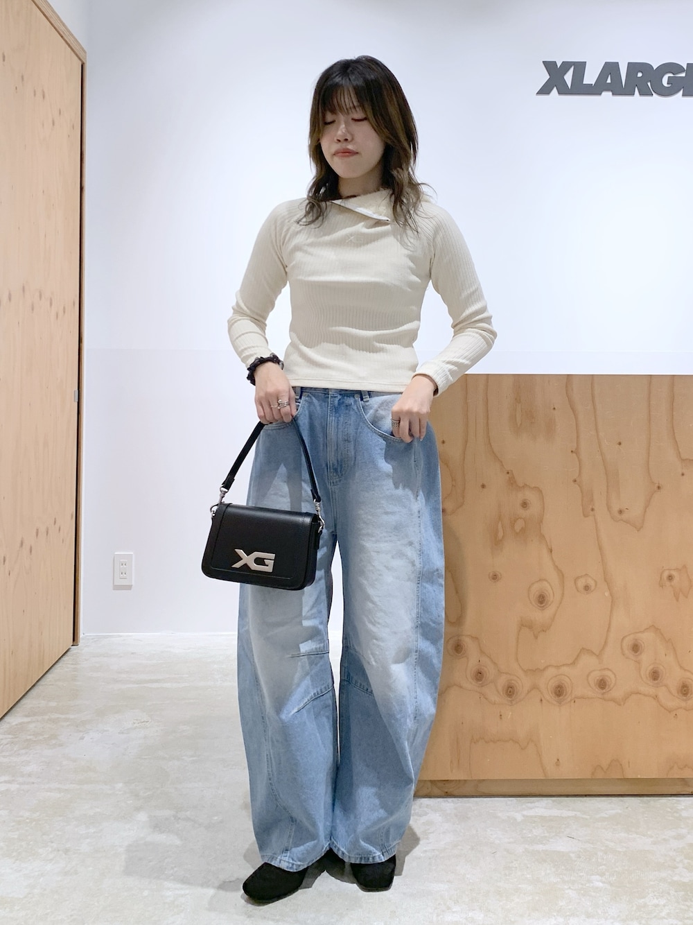 ホワイト系のパーカー、ブルー系のデニムパンツ、ブラック系のショルダーバッグを着用したレディースの冬コーディネートの1枚目の写真