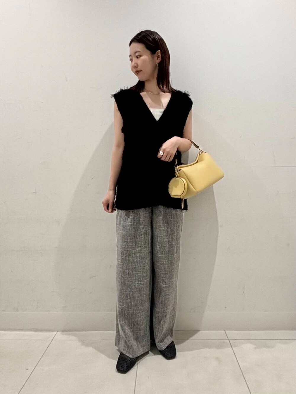 イエロー系のショルダーバッグ、ホワイト系のキャミソール、ブラック系のバレエシューズを着用したレディースの夏コーディネートの1枚目の写真