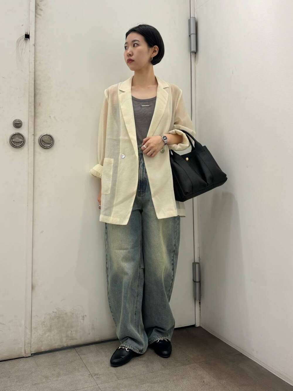 ブラック系のローファー、ブラック系のトートバッグ、ブルー系のデニムパンツを着用したレディースの秋コーディネートの1枚目の写真