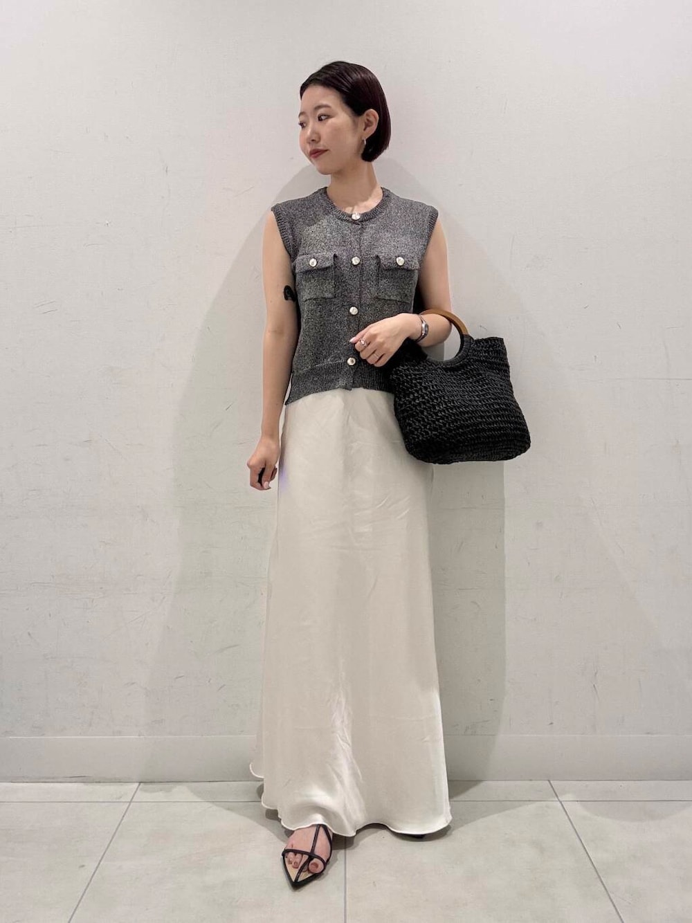 ホワイト系のスカート、ブラック系のトートバッグ、ブラック系のサンダルを着用したレディースの夏コーディネートの1枚目の写真
