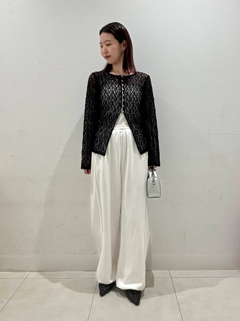 シルバー系のハンドバッグ、ホワイト系のキャミソール、ブラック系のサンダルを着用したレディースの夏コーディネートの1枚目の写真