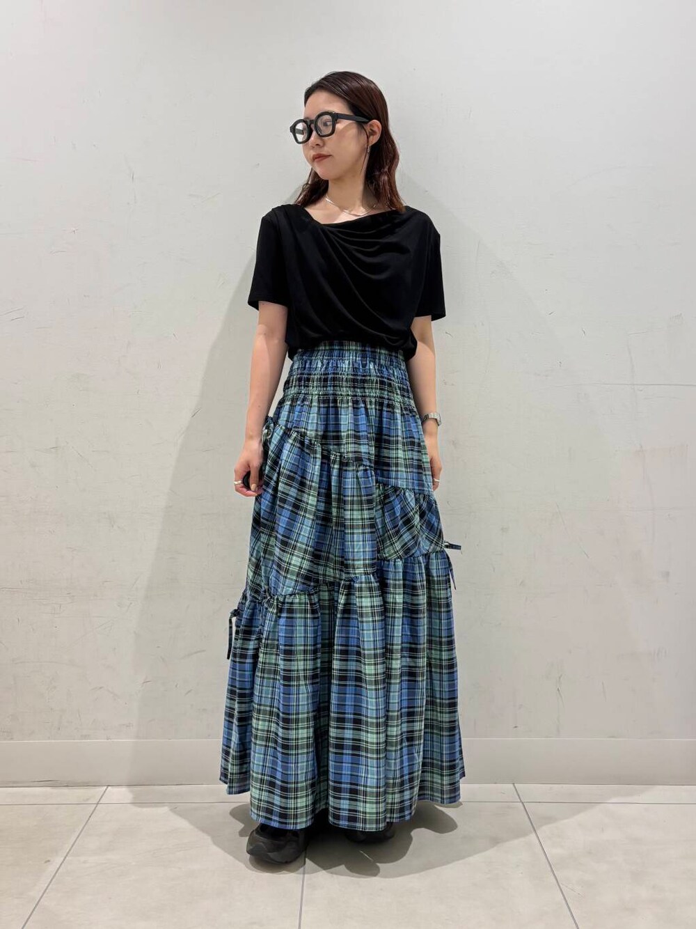 ブルー系のスカート、ブラック系のTシャツ/カットソー、ブラック系のメガネを着用したレディースの夏コーディネートの1枚目の写真