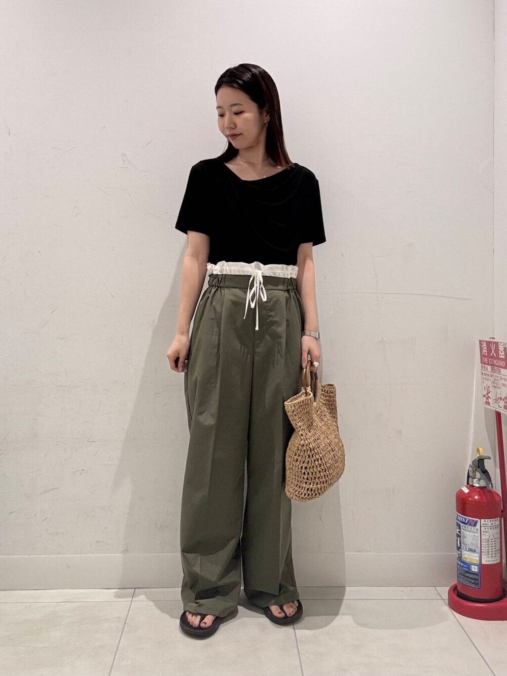 ベージュ系のトートバッグ、グリーン系のその他パンツ、ブラック系のTシャツ/カットソーを着用したレディースの夏コーディネートの1枚目の写真