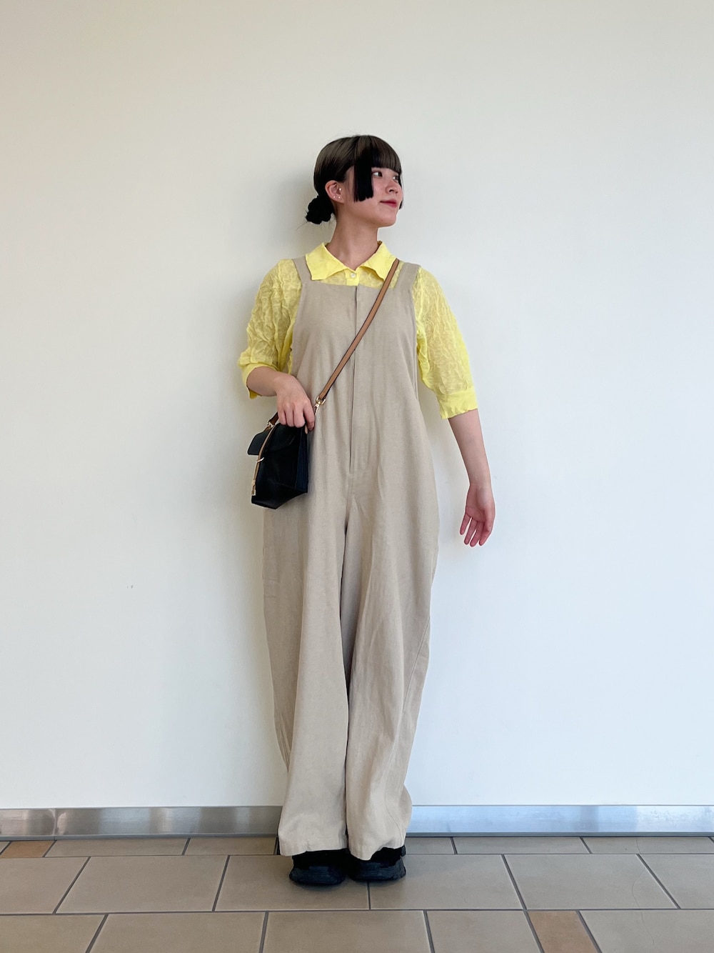 ベージュ系のサロペット/オーバーオール、イエロー系のニット/セーター、ブラック系のショルダーバッグを着用したレディースの夏コーディネートの1枚目の写真