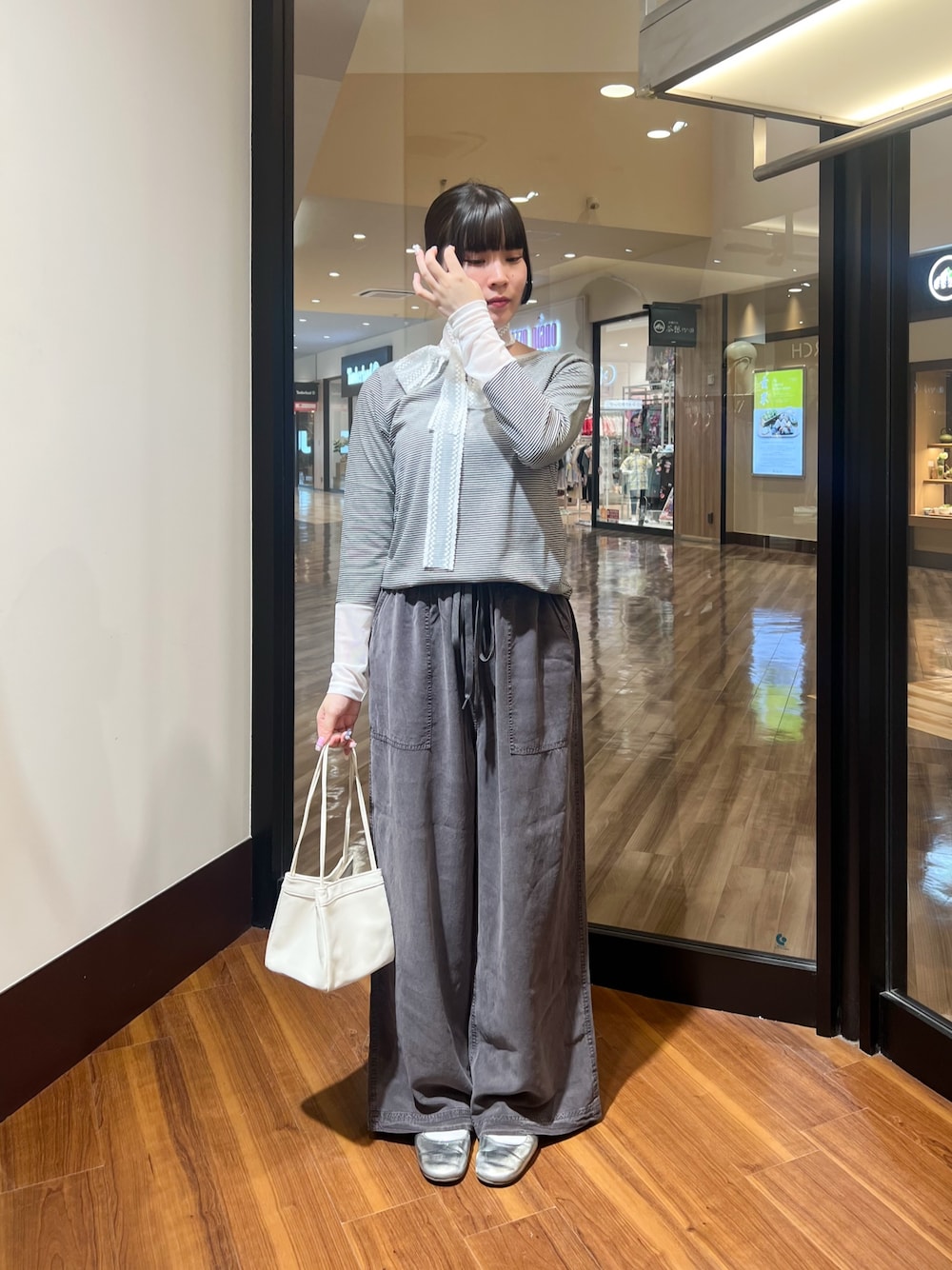 ホワイト系のTシャツ/カットソー、グレー系のその他パンツ、ホワイト系のハンドバッグを着用したレディースの秋コーディネートの1枚目の写真