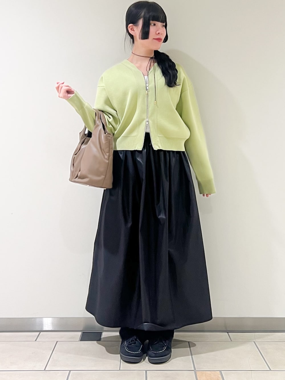 ブラック系のスカート、グリーン系のカーディガン/ボレロ、ホワイト系のタンクトップを着用したレディースの春コーディネートの1枚目の写真