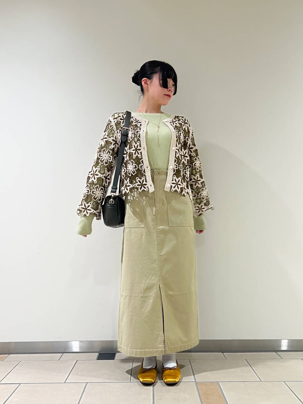イエロー系のバレエシューズ、グリーン系のショルダーバッグ、グリーン系のTシャツ/カットソーを着用したレディースの冬コーディネートの1枚目の写真