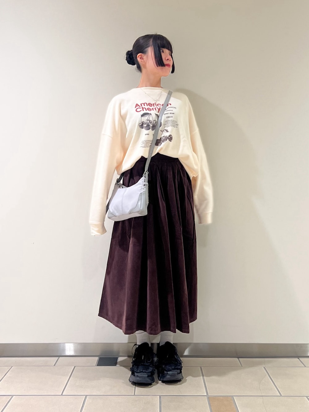 ホワイト系のTシャツ/カットソー、ブラウン系のスカート、グレー系のショルダーバッグを着用したレディースの秋コーディネートの1枚目の写真