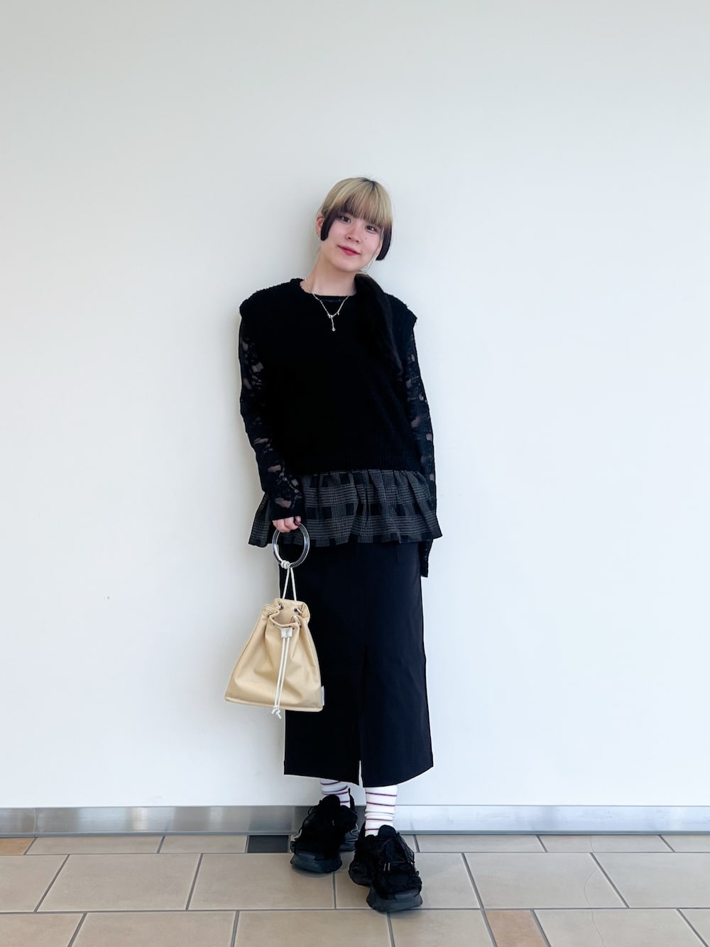 イエロー系のショルダーバッグ、ブラック系のスカート、ブラック系のTシャツ/カットソーを着用したレディースの秋コーディネートの1枚目の写真