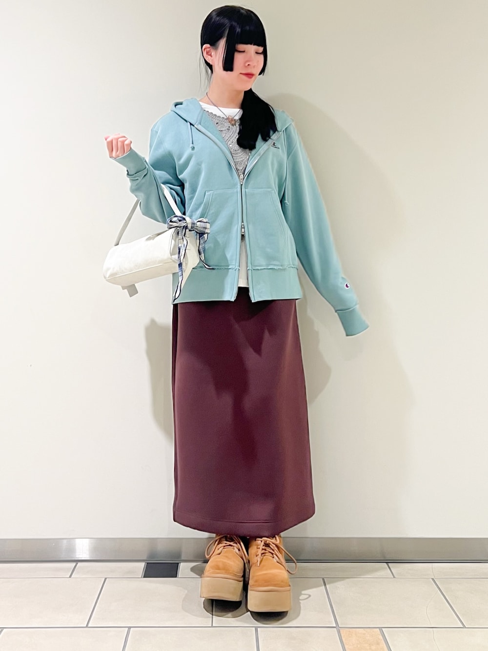 グレー系のTシャツ/カットソー、ブラウン系のスカート、グリーン系のパーカーを着用したレディースの春コーディネートの1枚目の写真