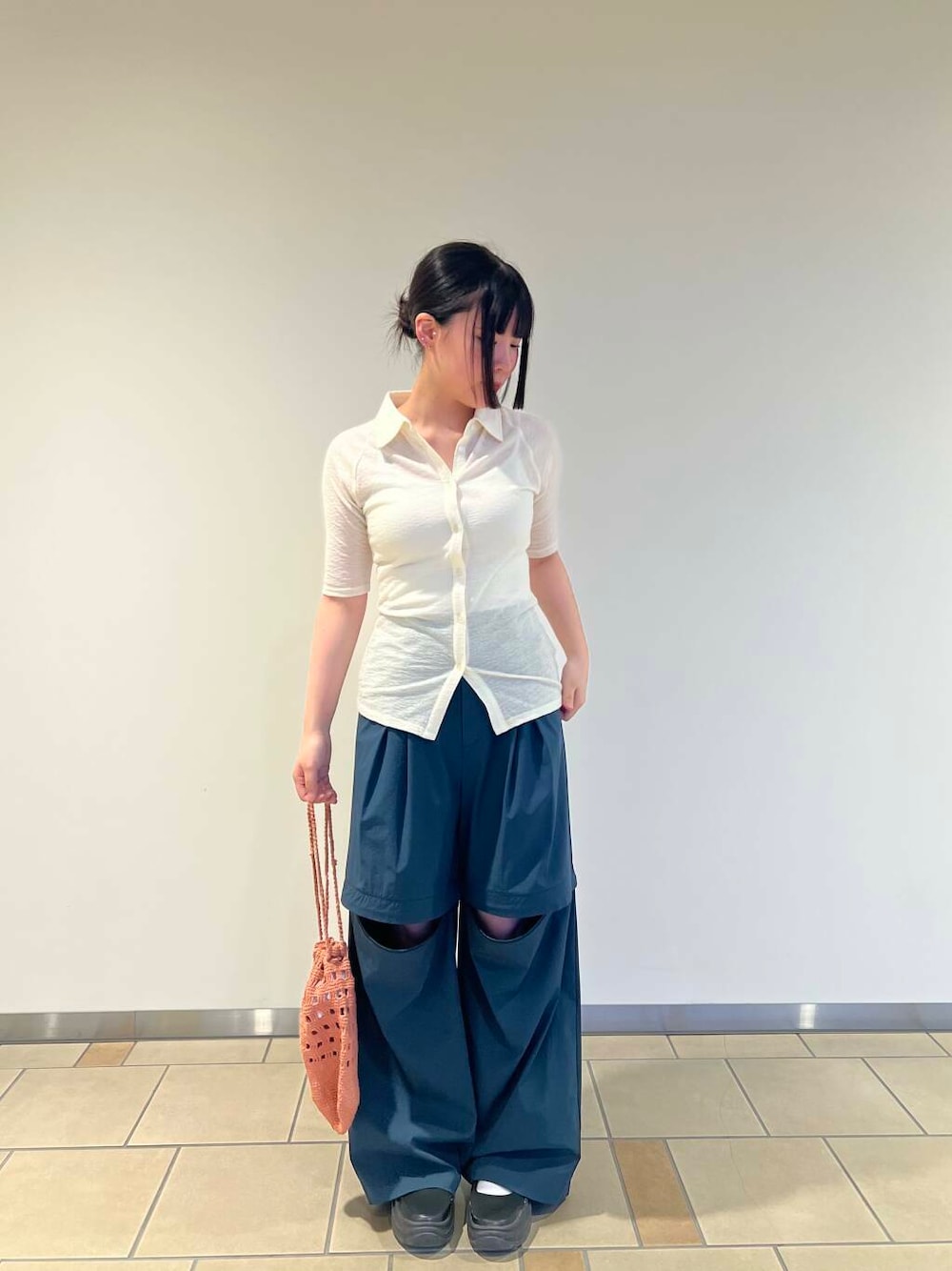 オレンジ系のハンドバッグ、グリーン系のその他パンツ、ホワイト系のカーディガン/ボレロを着用したレディースの秋コーディネートの1枚目の写真