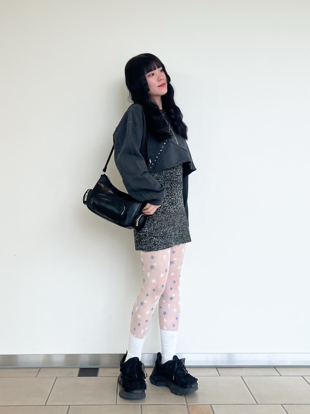 グレー系のスウェット、ブラック系のベスト、ブラック系のショルダーバッグを着用したレディースの春コーディネートの1枚目の写真