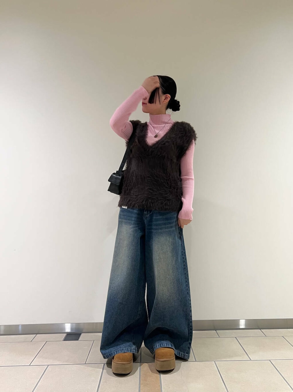 ピンク系のニット/セーター、ブラック系のハンドバッグ、ブルー系のデニムパンツを着用したレディースの冬コーディネートの1枚目の写真