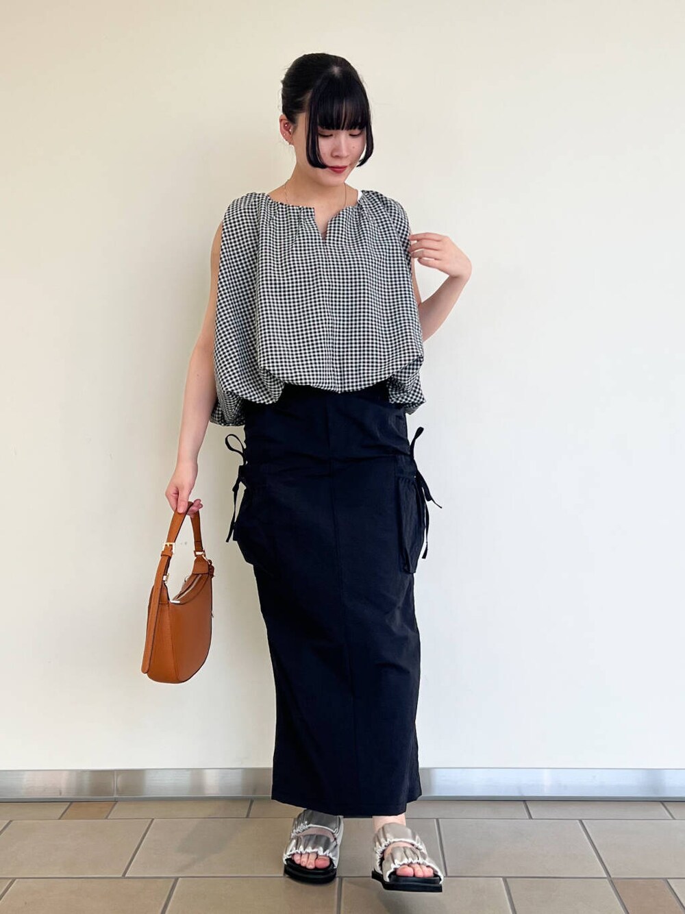 グレー系のサンダル、ブラック系のスカート、ホワイト系のシャツ/ブラウスを着用したレディースの夏コーディネートの1枚目の写真