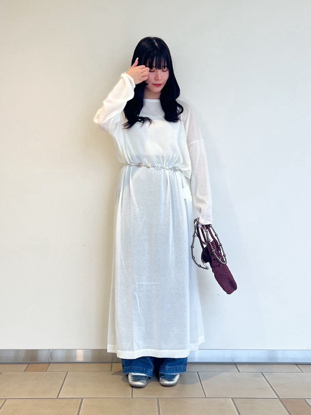 ホワイト系のワンピース、ブラウン系のショルダーバッグ、ブルー系のデニムパンツを着用したレディースの秋コーディネートの1枚目の写真