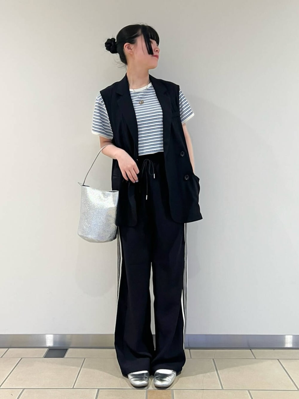 シルバー系のハンドバッグ、ブラック系のベスト、ブルー系のTシャツ/カットソーを着用したレディースの春コーディネートの1枚目の写真