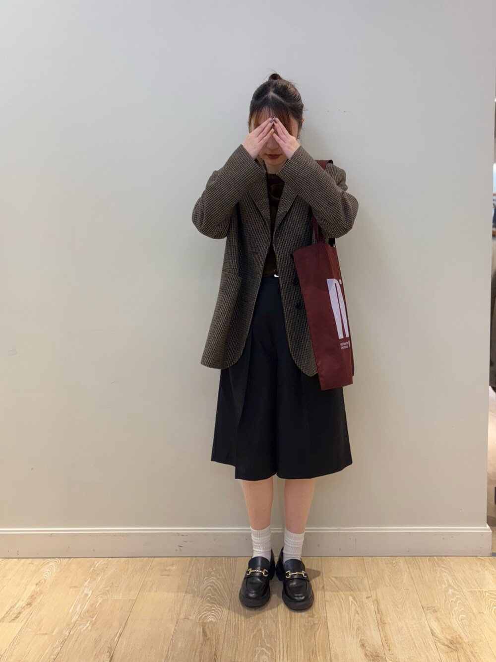 レッド系のトートバッグ、ブラック系のその他パンツ、ブラウン系のTシャツ/カットソーを着用したレディースの秋コーディネートの1枚目の写真